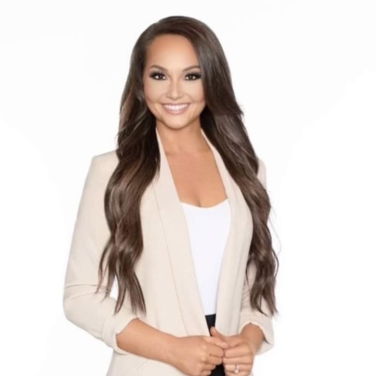 Taylor Dirk Smiling woman in a light blazer with long hair, posing confidently.