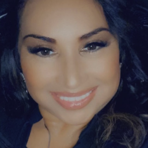 Alexs Striba Smiling woman with long dark hair and natural makeup, looking directly at the camera.