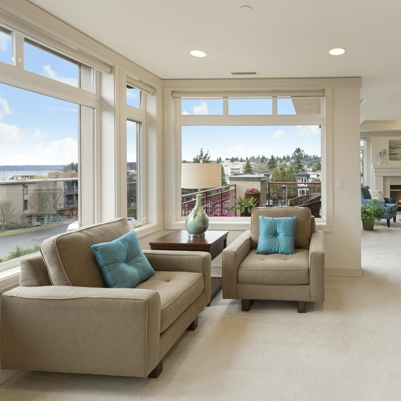 Capture & Close Real Estate Imagery Bright living room with large windows, two armchairs, and a table. Scenic view outside.